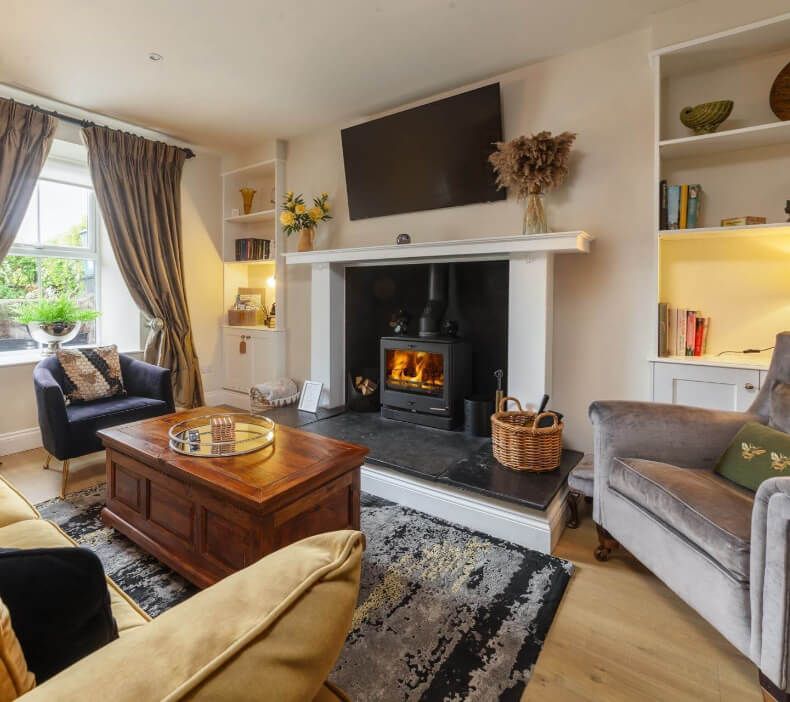 Living room at Cascadia House with a log burner and built-in shelving
